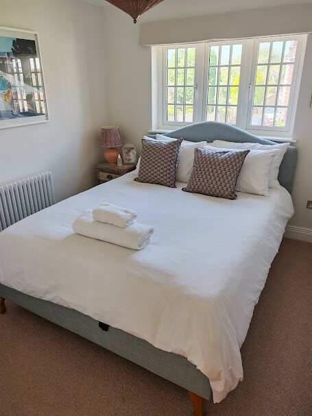 Bright guest-ready bedroom with fresh white bedding and neatly folded towels