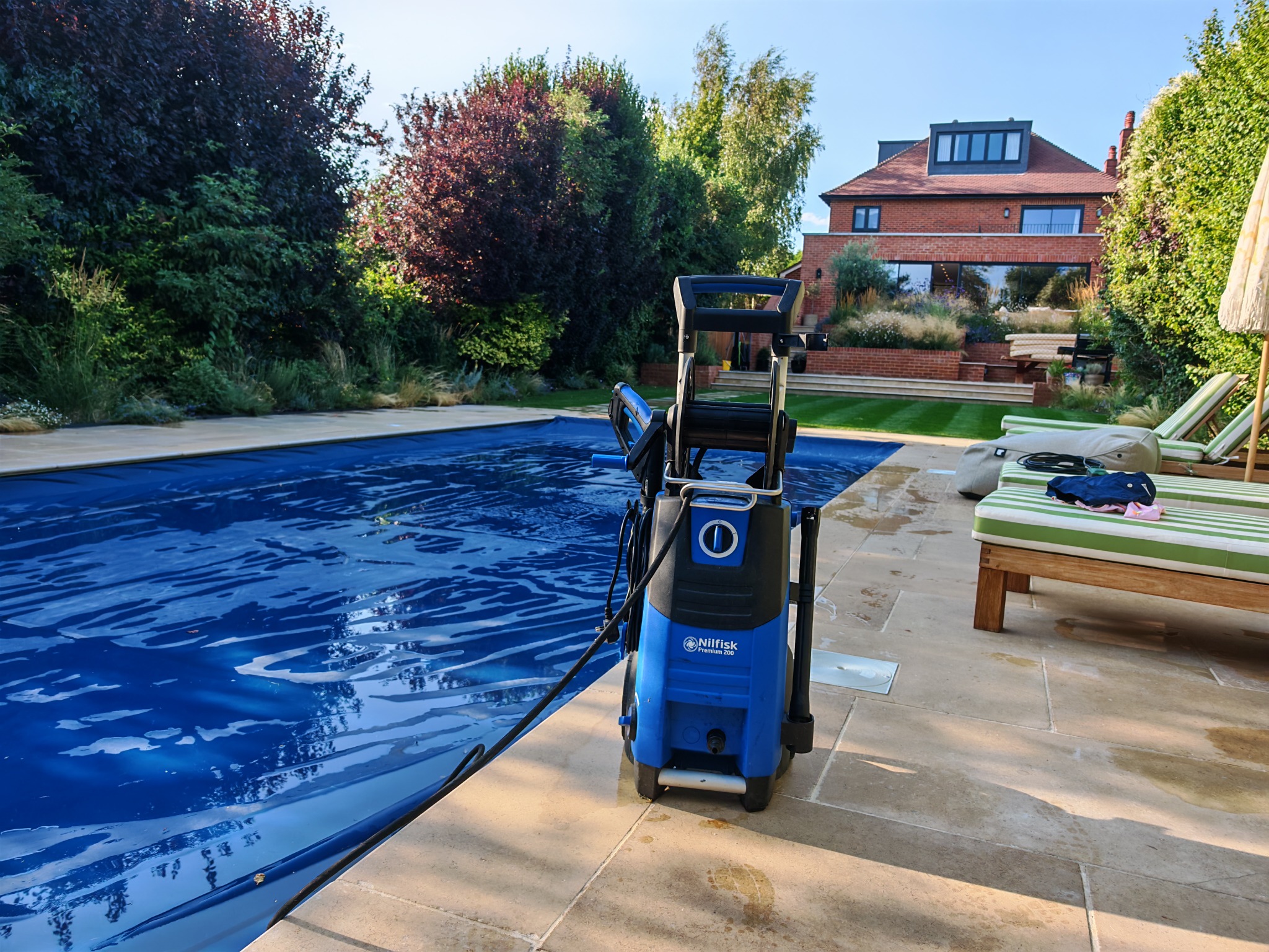 Professional pressure washer beside a swimming pool surround