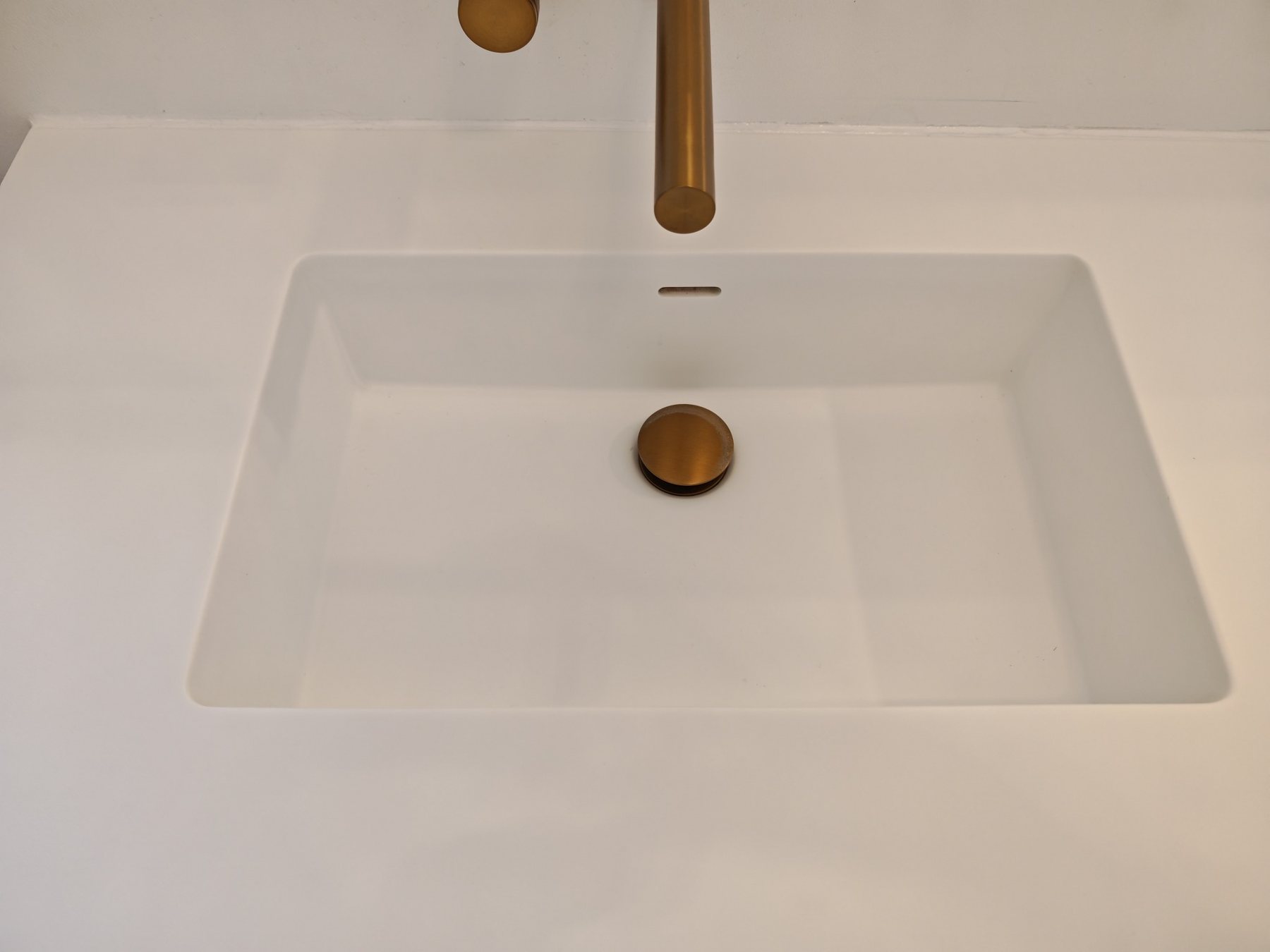 Clean white sink with brushed brass fittings